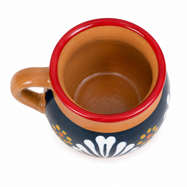 A hand-painted ceramic mug with a brown handle and interior, featuring a red rim, a dark blue exterior with white floral patterns, and small yellow and orange dots, shown on a white background.