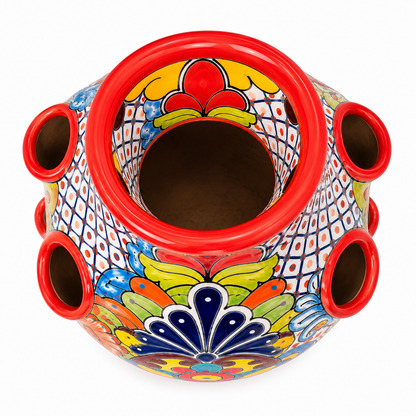 A colorful hand-painted ceramic planter pot with multiple side drainage holes, featuring a vibrant Mexican Talavera style design with red, blue, yellow, green, and white patterns on a white background.
